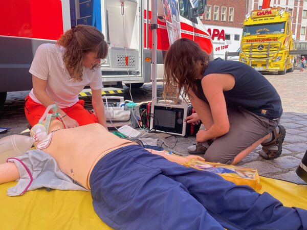 Rettungsassistentin Yasmin Ledder zeigt einem interessierten Jungen, der Feuerwehrmann werden m&ouml;chte, die Reanimation eines Menschen an einem Dummy